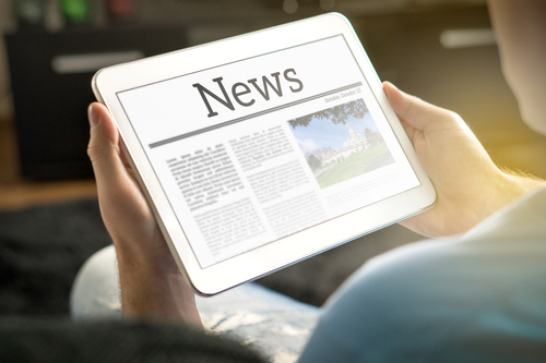 Picture of a man holding a smart tablet that says "News" on the screen.